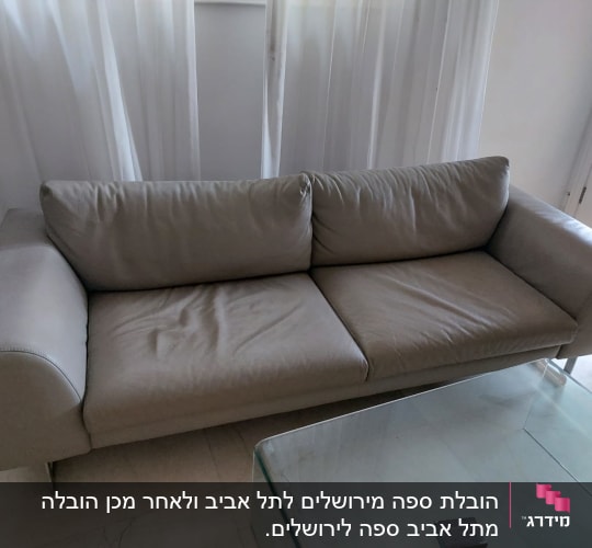 ספה אפורה ליד שולחן זכוכית בחדר מואר